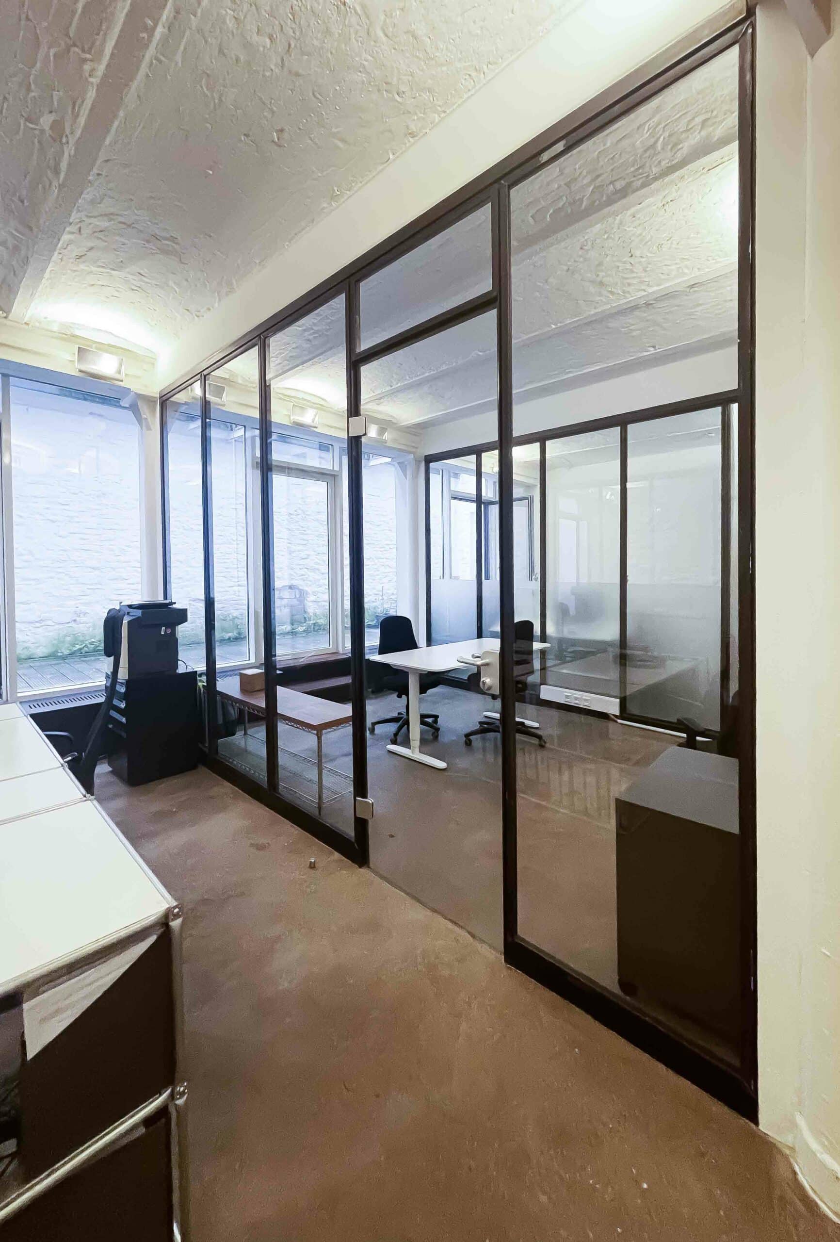 Büro, das mit Glaswänden abgetrennt ist. Office mit Glastüren, Lofttüren, Trennwand aus Glas. Helle Raumaufteilung für Büro.